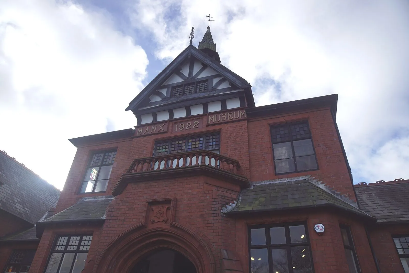 The red-brick and half-timbered original entrance of the Manx Museum in Douglas, with “Manx Museum 1922” carved above an arched doorway