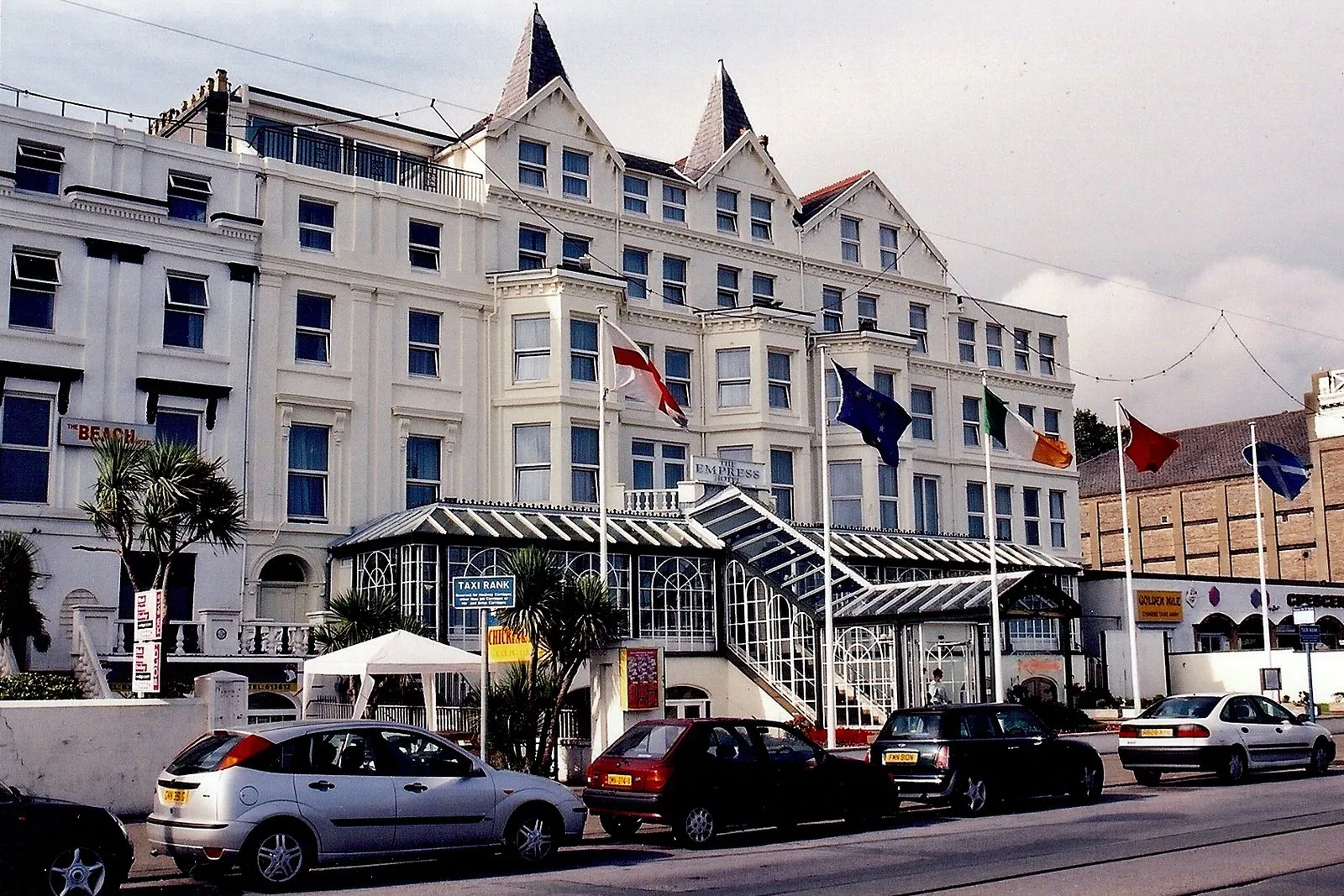 The white-painted Empress Hotel on Central Promenade, Douglas, with flags and a glass veranda