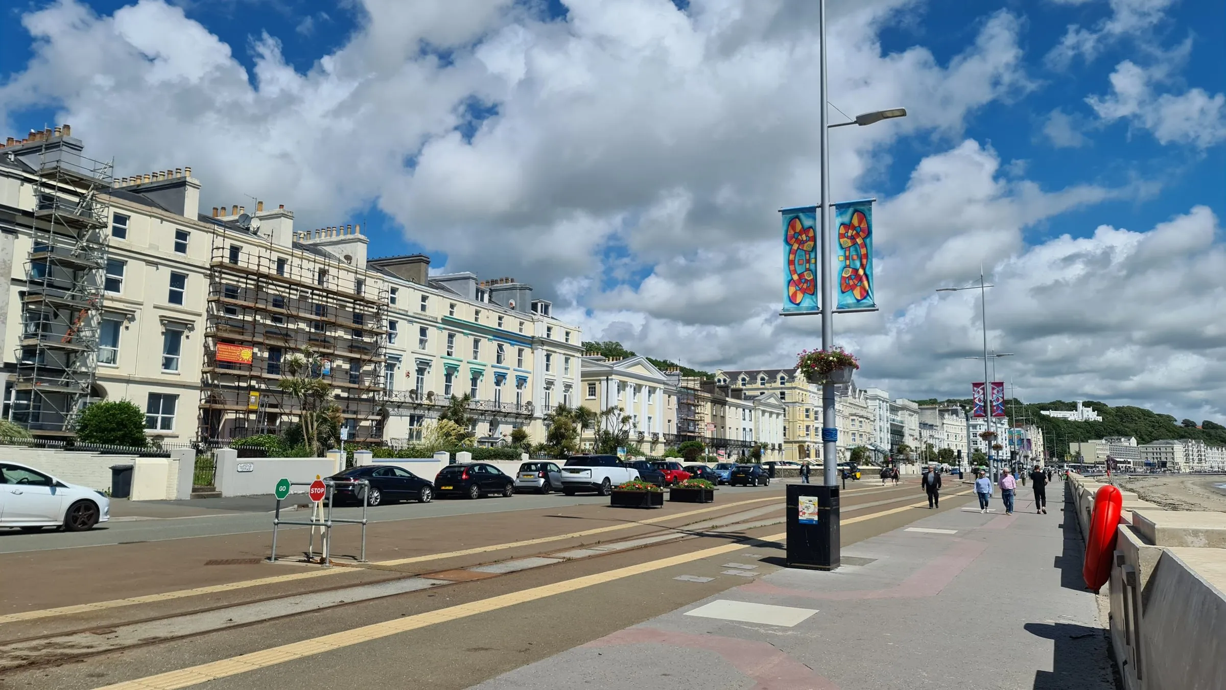 Central Promenade in Douglas, a long row of cream Victorian hotels and guest houses facing the bay, some under scaffolding