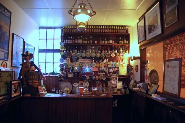 A small wood-panelled brewery bar with bottles and beer mats lining the shelves behind the counter