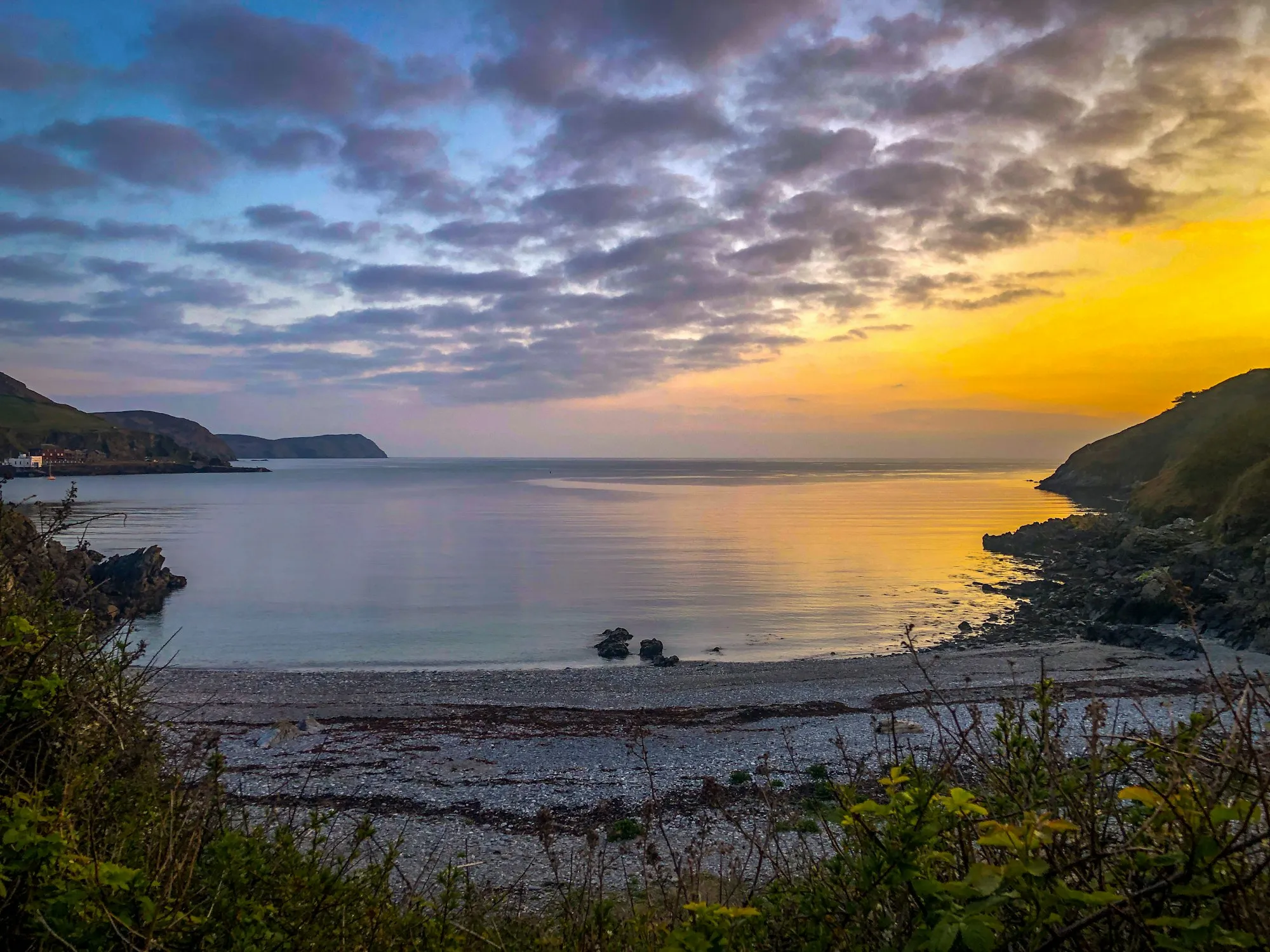Spaldrick beach in the evening, a calm cove between rocky headlands under a golden sky