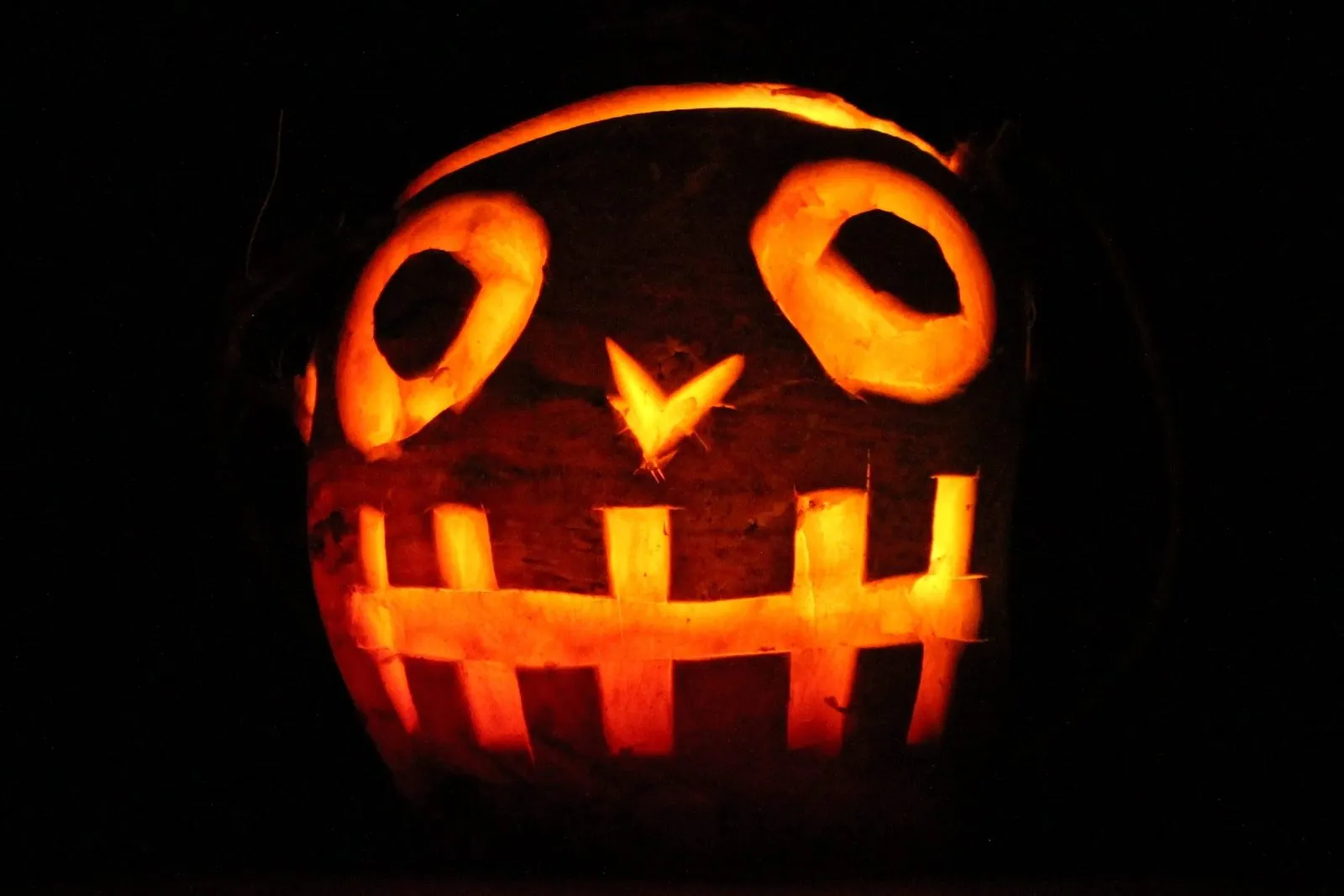 A turnip lantern carved with a grinning face and round eyes, glowing orange in the dark
