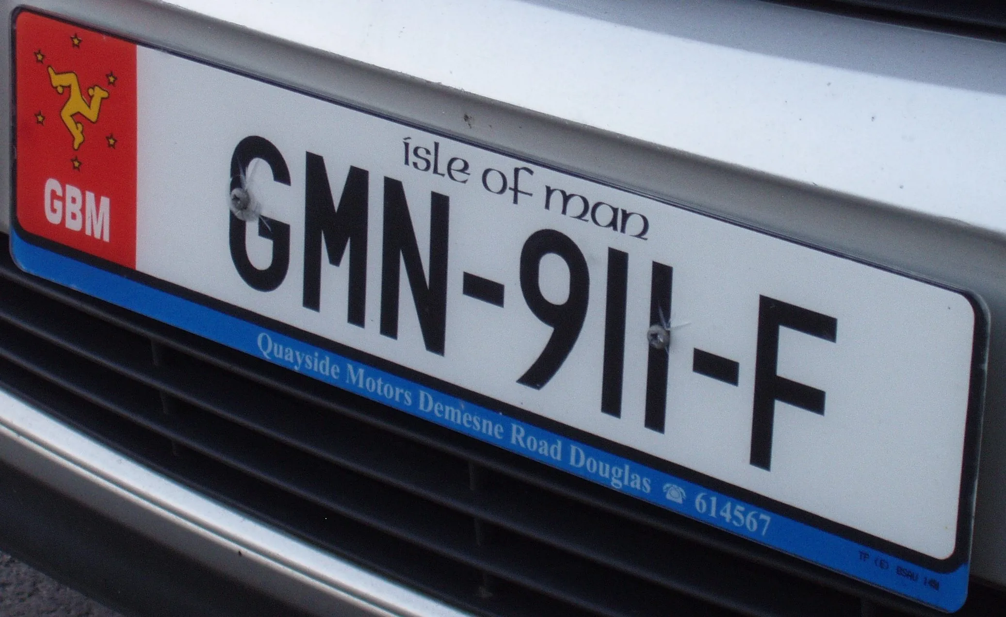 A white Isle of Man number plate reading GMN-911-F, with the red Manx flag, the three legs symbol and GBM on the left