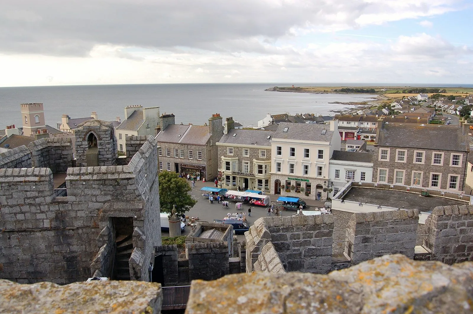 The rooftops of Castletown’s Market Square seen from Castle Rushen’s battlements, with market stalls below and the sea beyond
