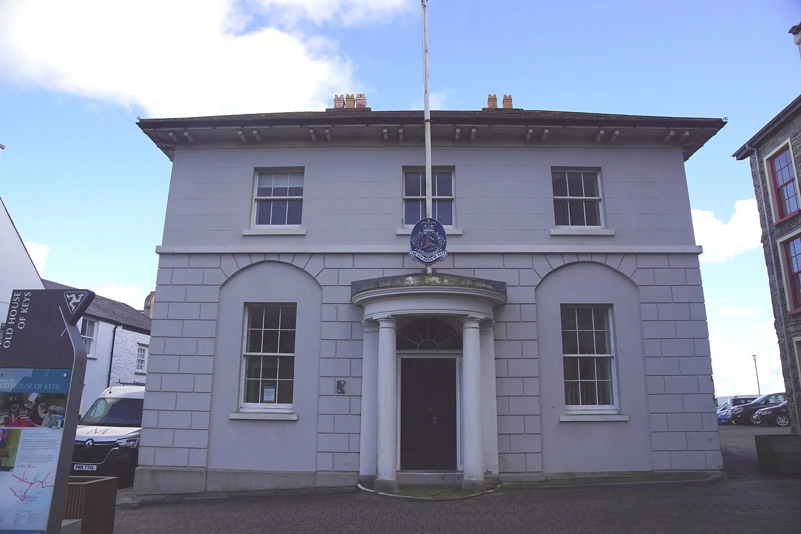 The Old House of Keys, a pale grey two-storey Georgian building with a columned porch and the Manx arms above the door