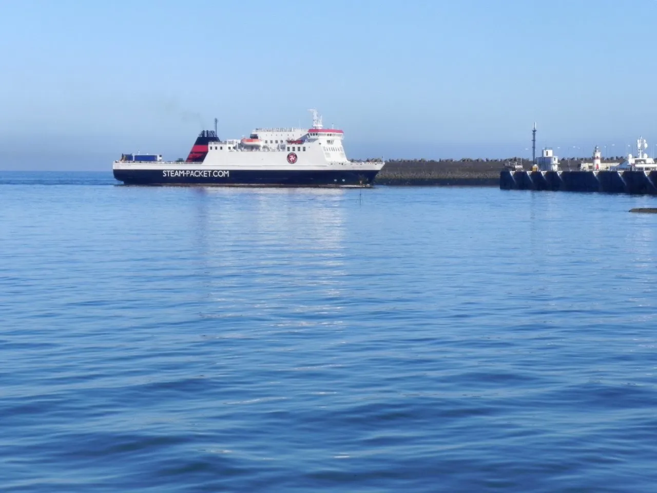 The Steam Packet ferry Ben-my-Chree, white with a dark hull and red funnel, entering Douglas harbour on a calm blue sea