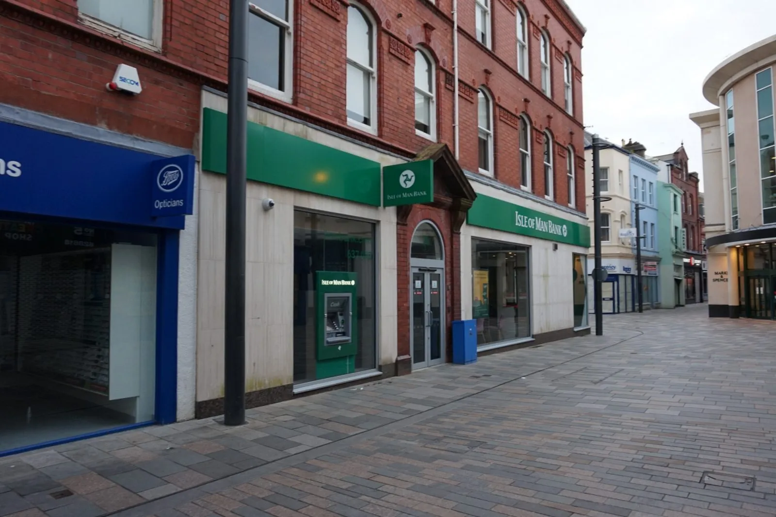 Strand Street in Douglas, a pedestrianised shopping street with an Isle of Man Bank branch and cash machine, a Boots opticians and Marks and Spencer beyond