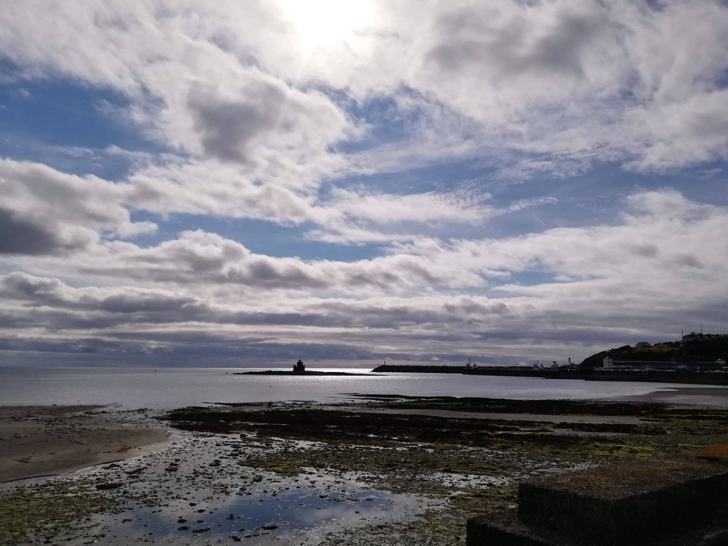 Douglas Bay at low tide under a big sky, with the Tower of Refuge on its rock and the harbour and Douglas Head beyond