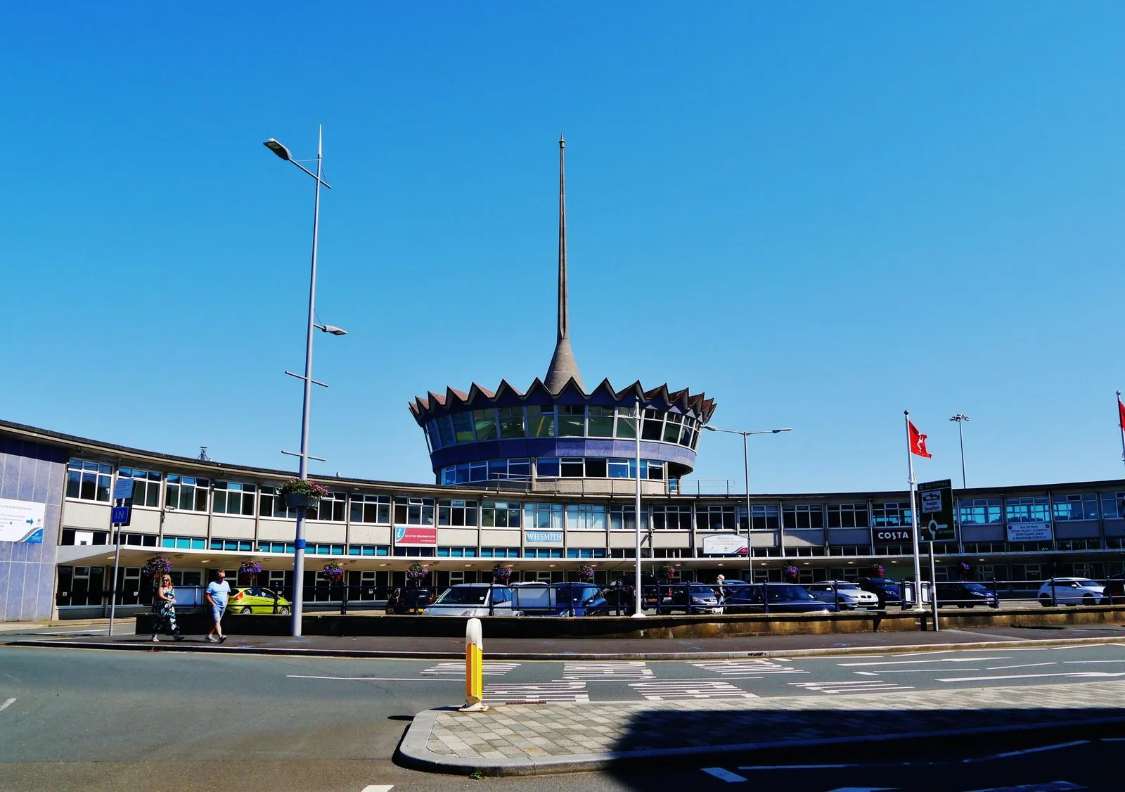 The Douglas Sea Terminal, a curved 1960s building with a crown-shaped roof and a tall spire, under a clear blue sky