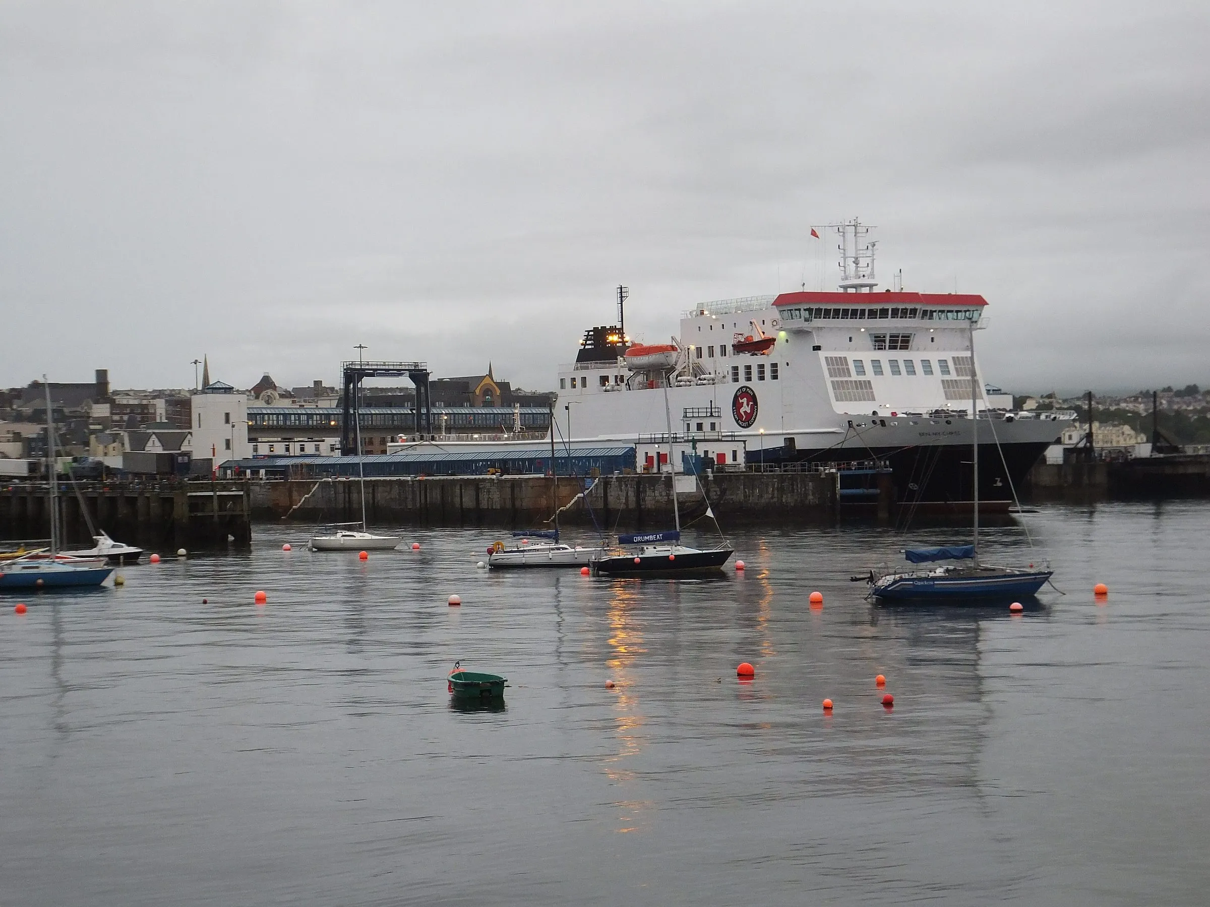 The Steam Packet ferry Ben-my-Chree, white with a red funnel top, berthed in Douglas harbour on a grey evening with small yachts moored in front
