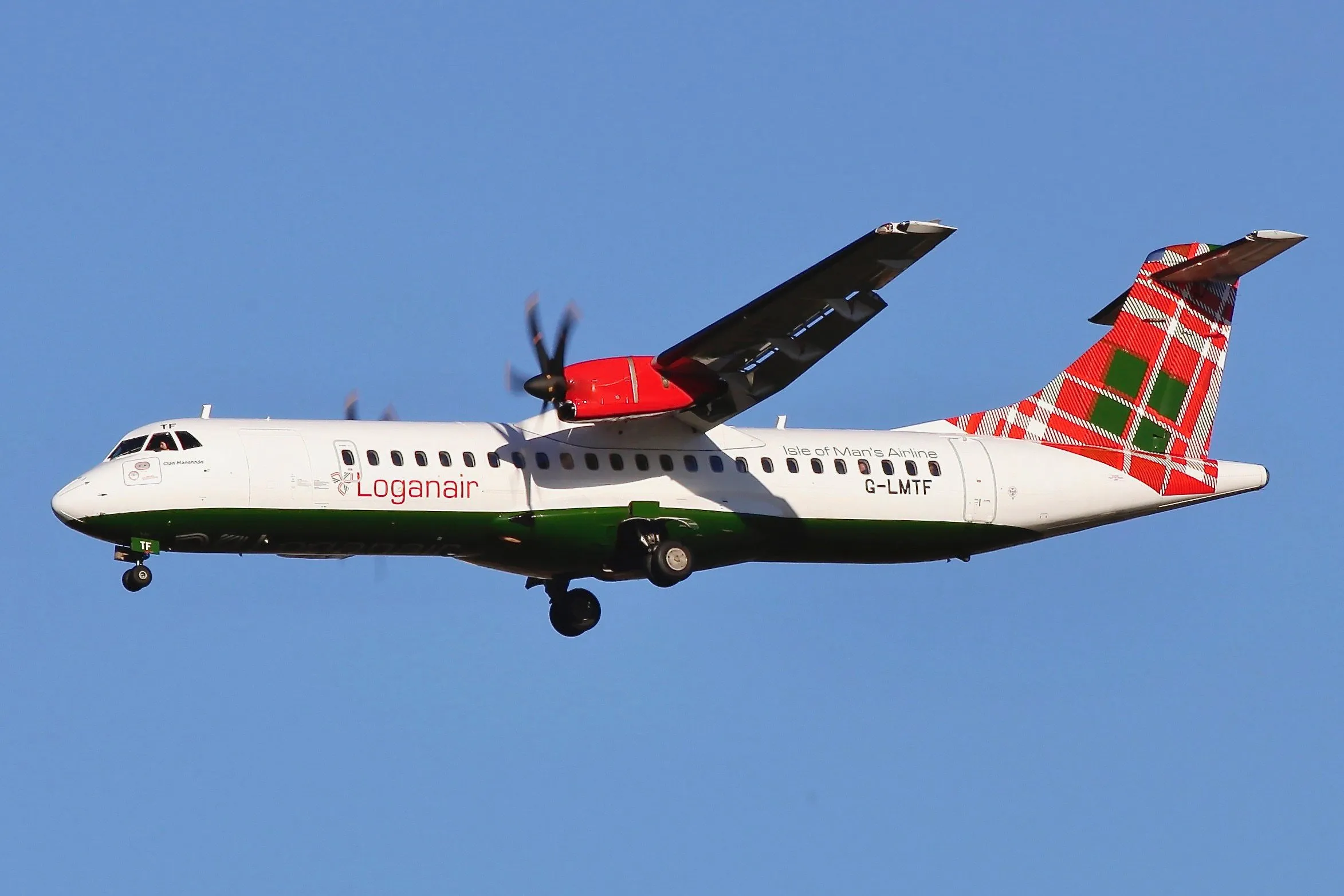 A Loganair ATR 72 turboprop in white with a red and green tartan tail, marked "Isle of Man's Airline", coming in to land