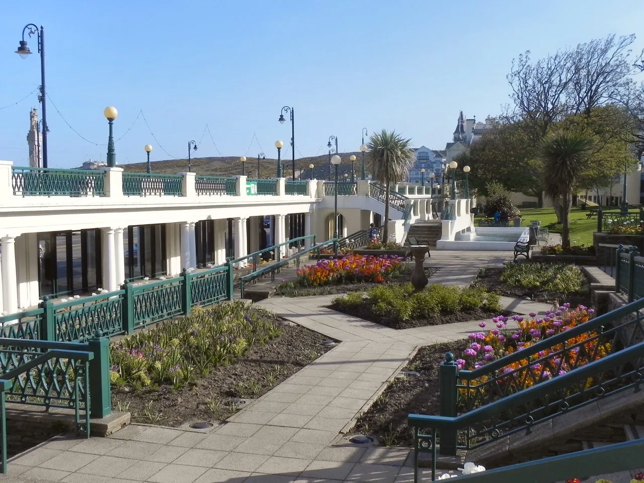 The Villa Marina Gardens in Douglas in spring, with white colonnades, green railings and flowerbeds of tulips around paved paths