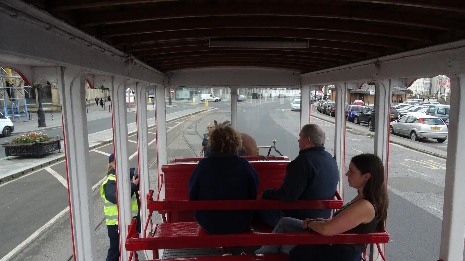 Looking forward from the top deck of a Douglas horse tram, over red wooden seats and passengers, towards the horse and the tram lines along Loch Promenade