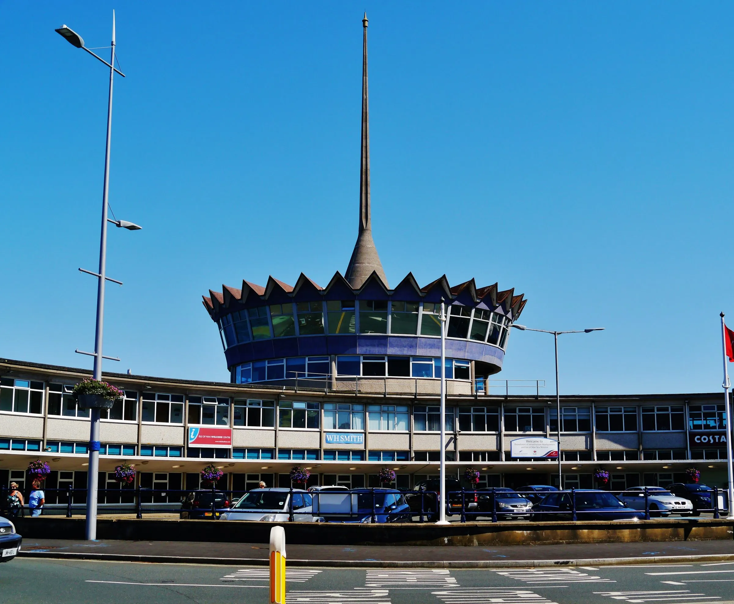 The front of Douglas Sea Terminal, a long 1960s building with a crown-shaped rotunda and tall spire on its roof, under a deep blue sky