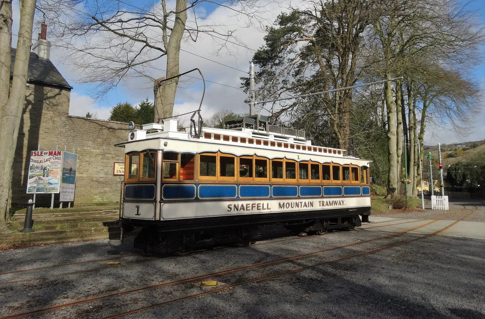 A cream and blue Snaefell Mountain Railway tram waiting at Laxey station under bare trees