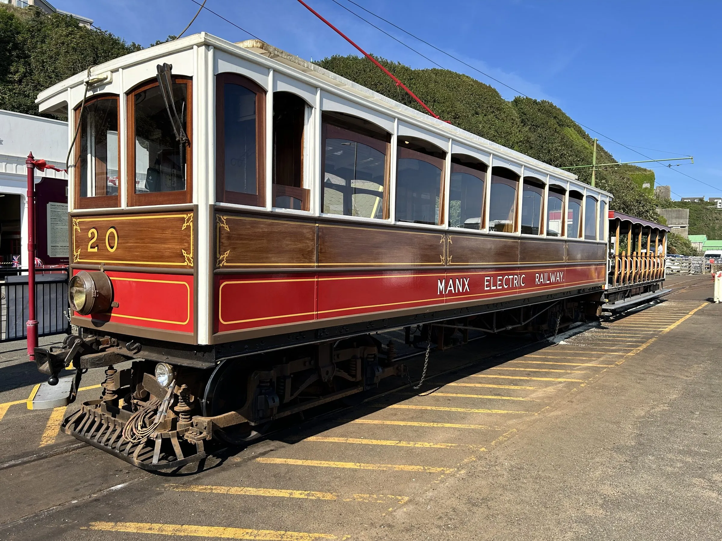 Manx Electric Railway tram number 20, in varnished wood and red livery, waiting at a platform in bright sunshine