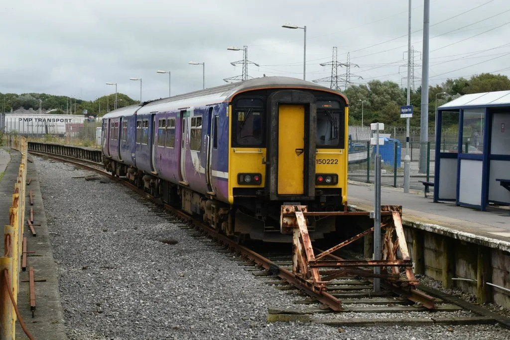 A purple Northern train standing at the buffers at Heysham Port station, with an empty platform and a bus-shelter-style waiting shelter
