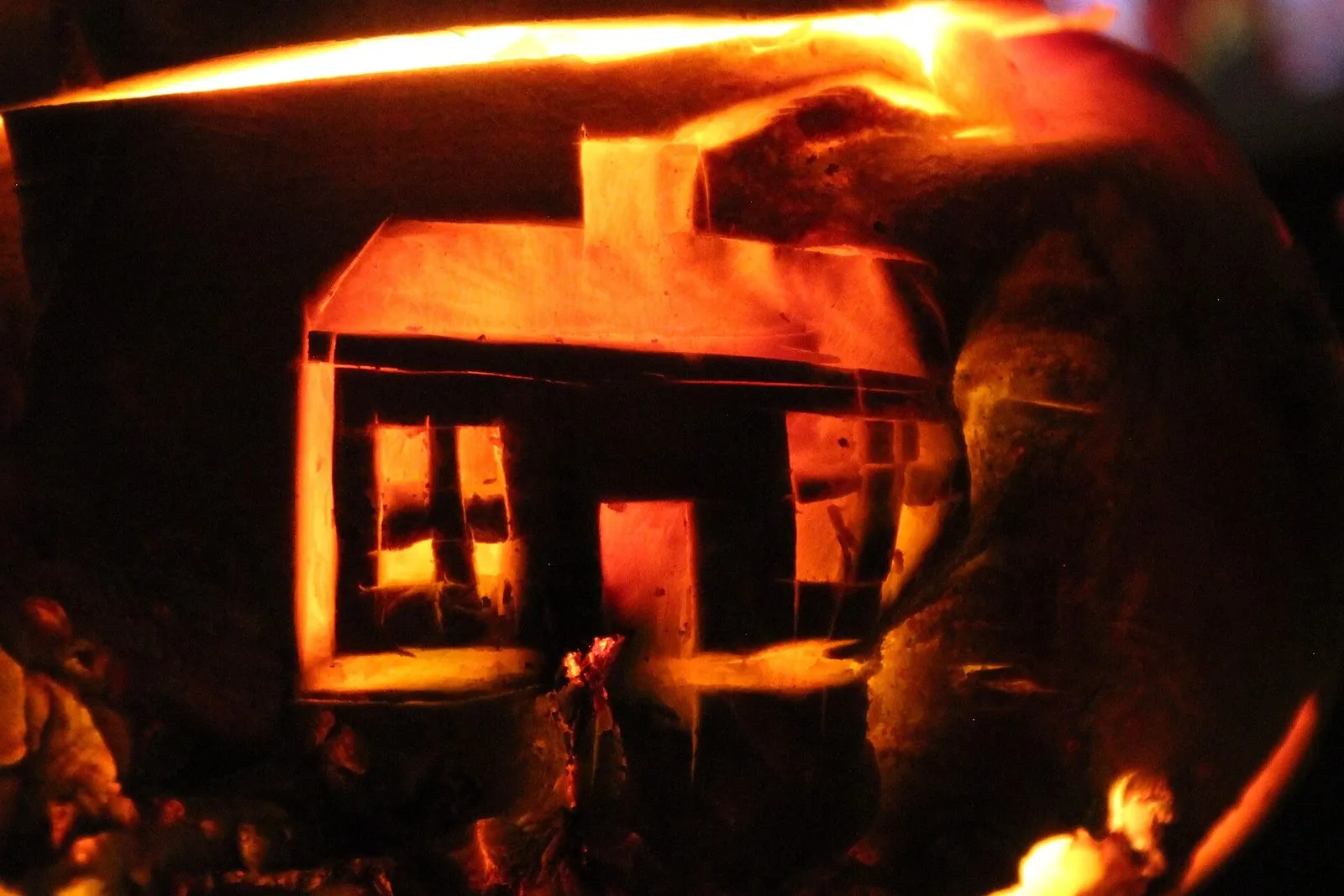 A turnip lantern lit from inside, carved with a small Manx cottage with a chimney, door and windows