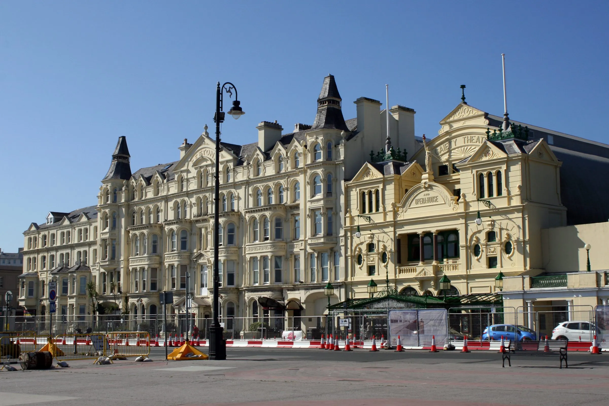 The cream Victorian frontage of the Sefton Hotel beside the ornate Gaiety Theatre on Harris Promenade, Douglas, under a clear blue sky