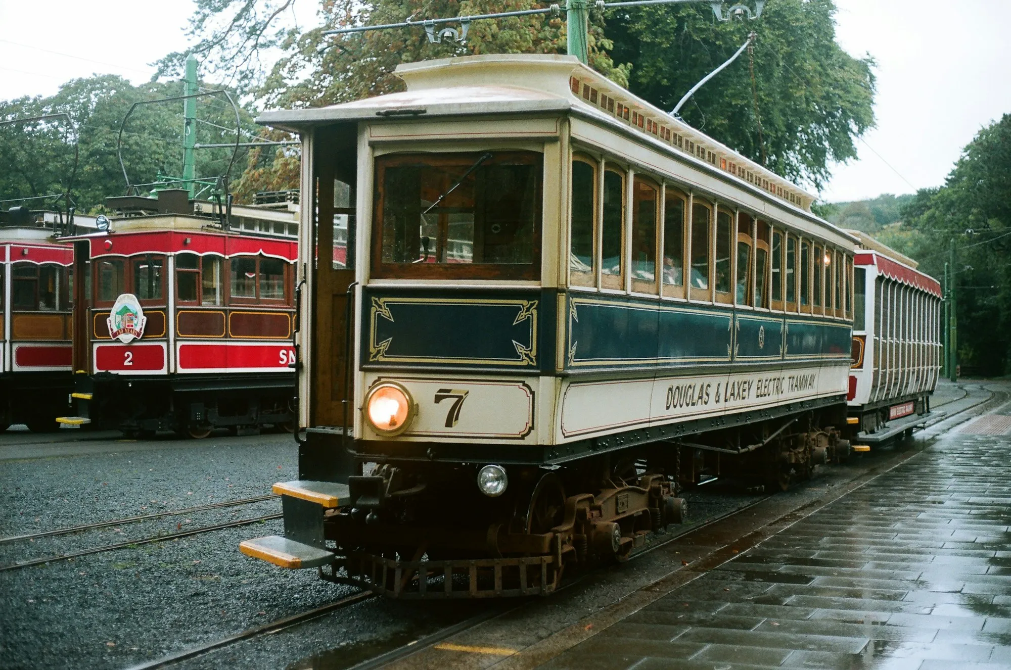 A vintage Douglas & Laxey Electric Tramway car at Laxey station on the Manx Electric Railway, with red Snaefell tramcars waiting behind it