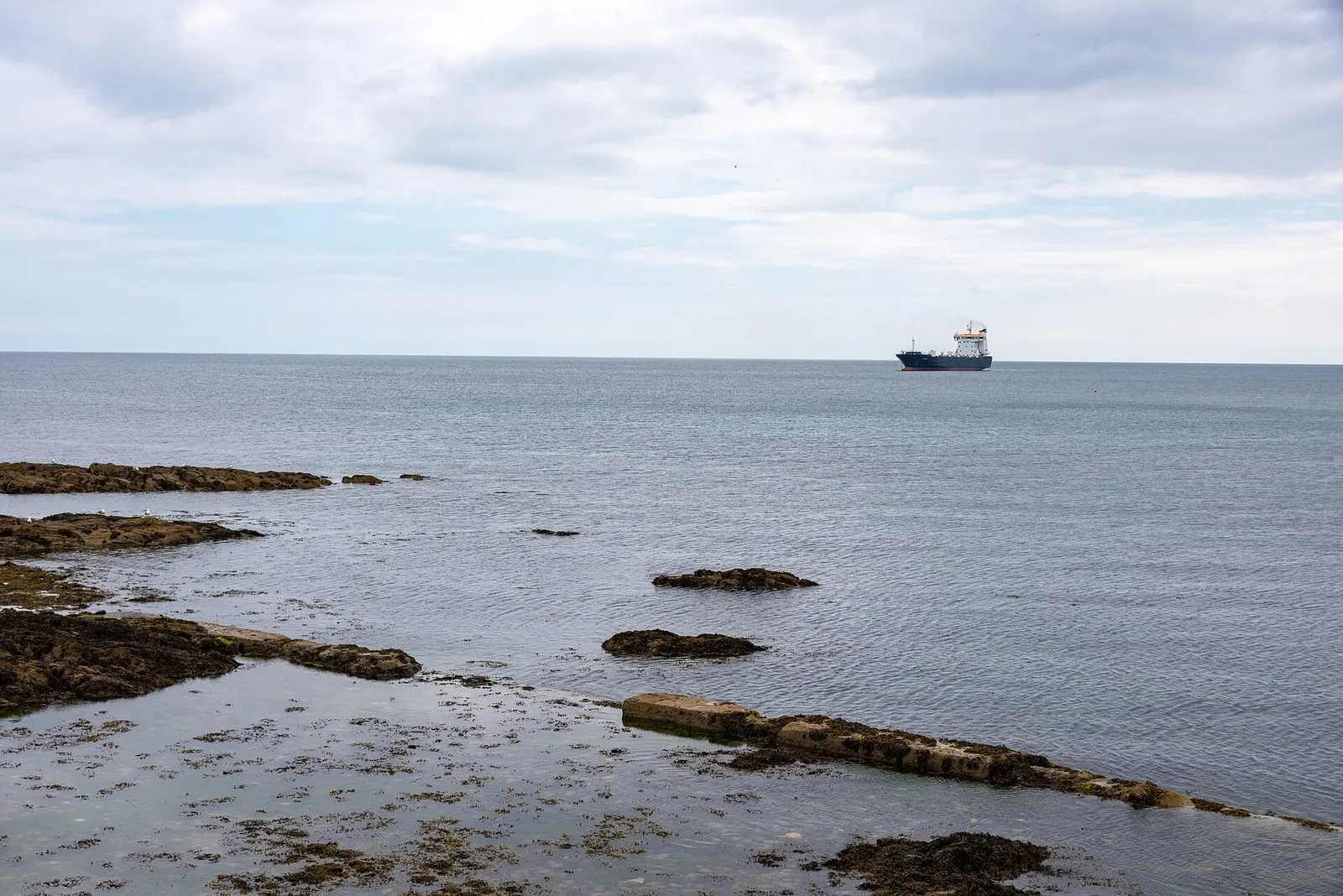 The Steam Packet freighter Arrow, a dark-hulled cargo ship with a white superstructure, at sea off Douglas under a grey sky