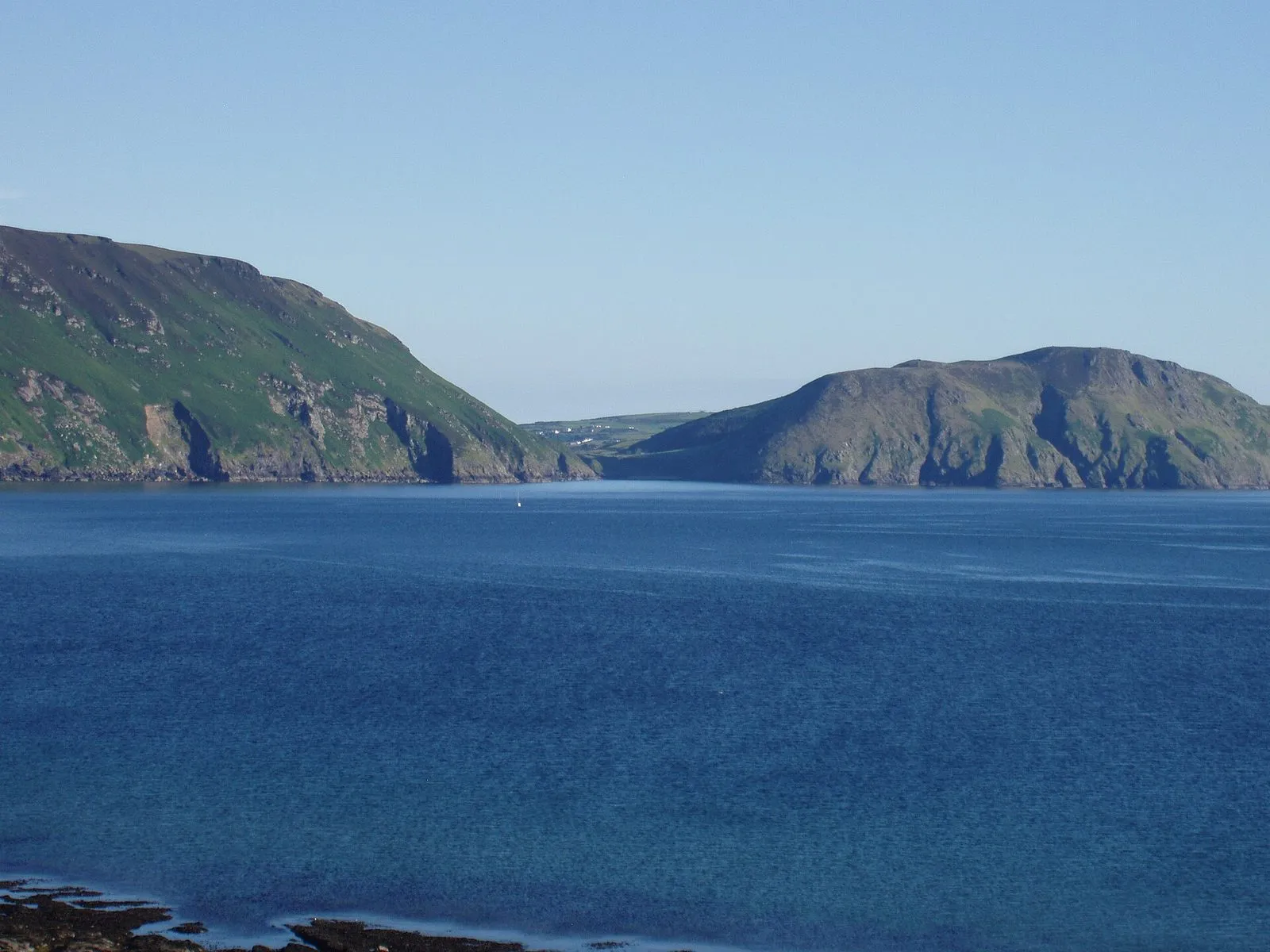 Two green headlands either side of a wide bay of deep blue sea, seen from Niarbyl on the west coast