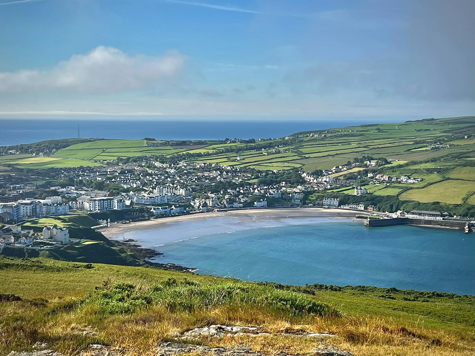 Port Erin from the hill above, the sandy bay curving round below the town with green fields and the sea beyond