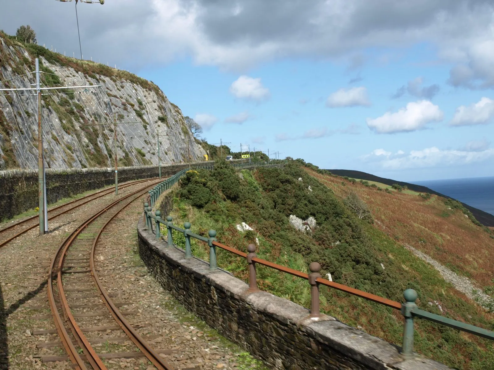 Manx Electric Railway tracks curving along a stone-walled ledge high above the sea near Bulgham Bay