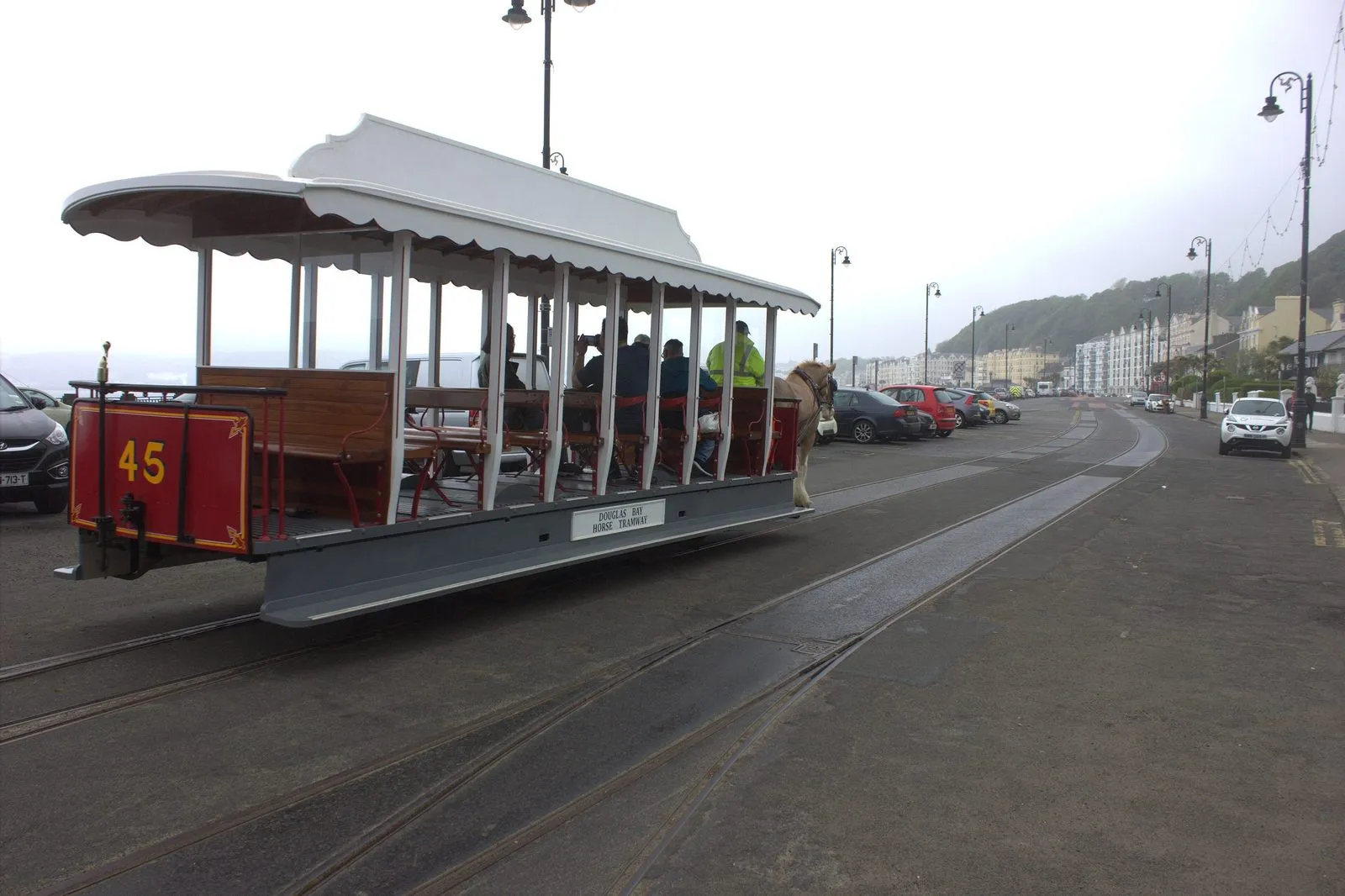 A single-deck horse tram with a canopy roof on rails along the Douglas promenade, hotels in the background