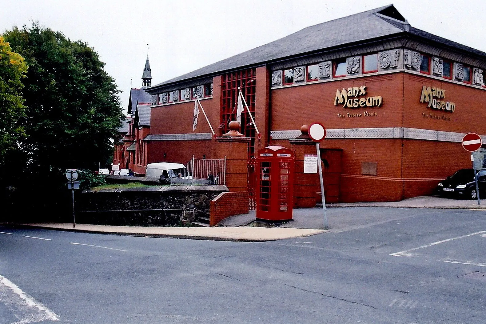 The red-brick Manx Museum building in Douglas, with a red phone box on the corner in front