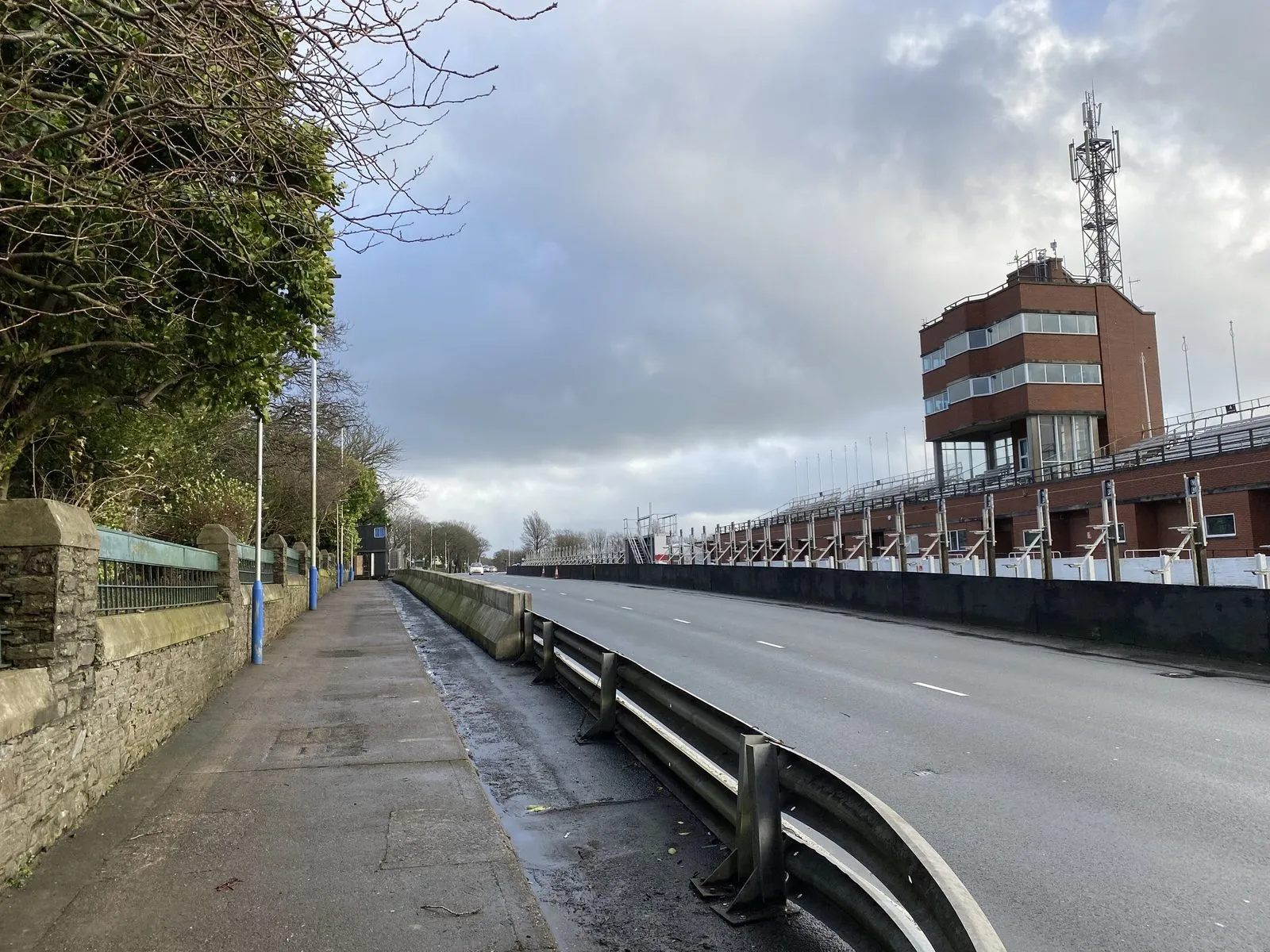 The TT Grandstand and race control tower on Glencrutchery Road in Douglas, seen along the empty course on a grey day