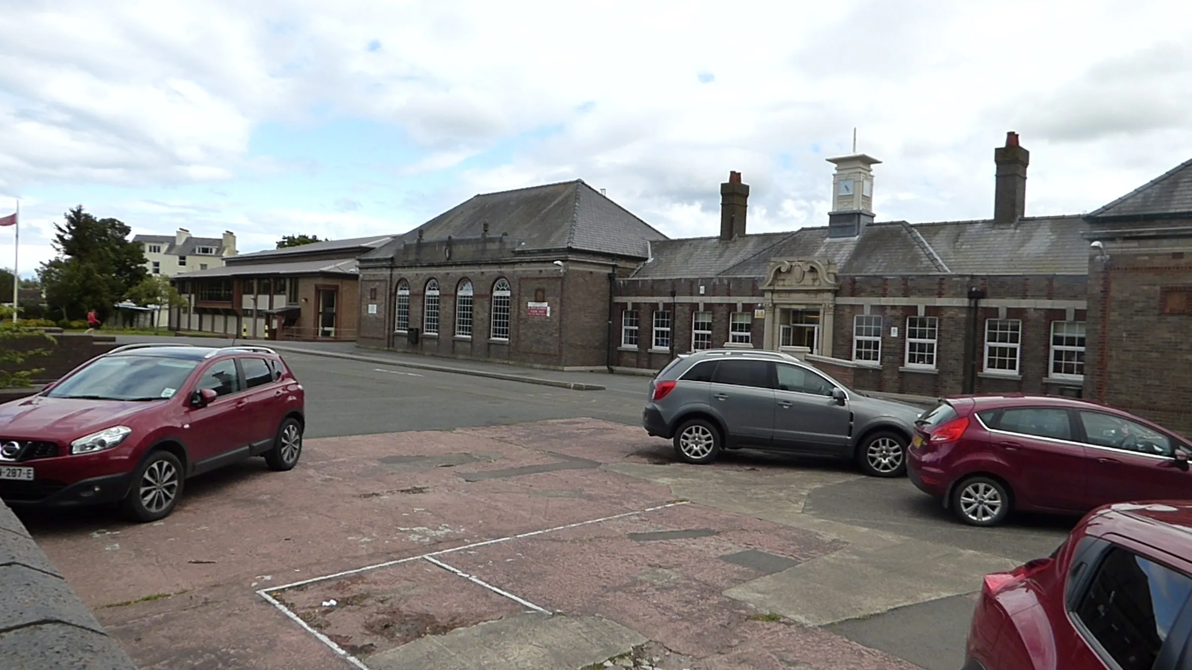 The red-brick buildings of Ramsey Grammar School, with a clock tower on the roof, seen across a car park