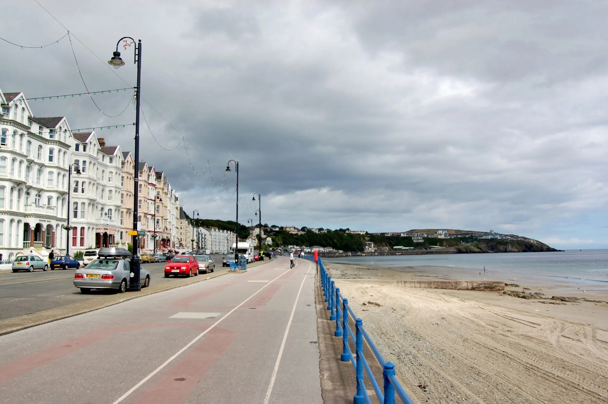 The white Victorian hotel terraces of Queens Promenade in Douglas curving along the bay towards Onchan Head under a grey sky