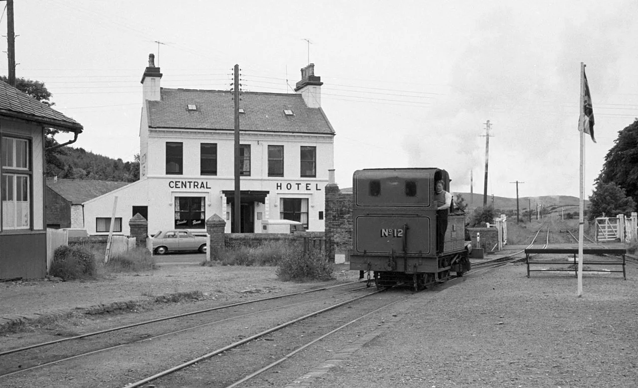 A black-and-white photograph of a small steam locomotive at St Johns station in 1968, with the Central Hotel behind the platform