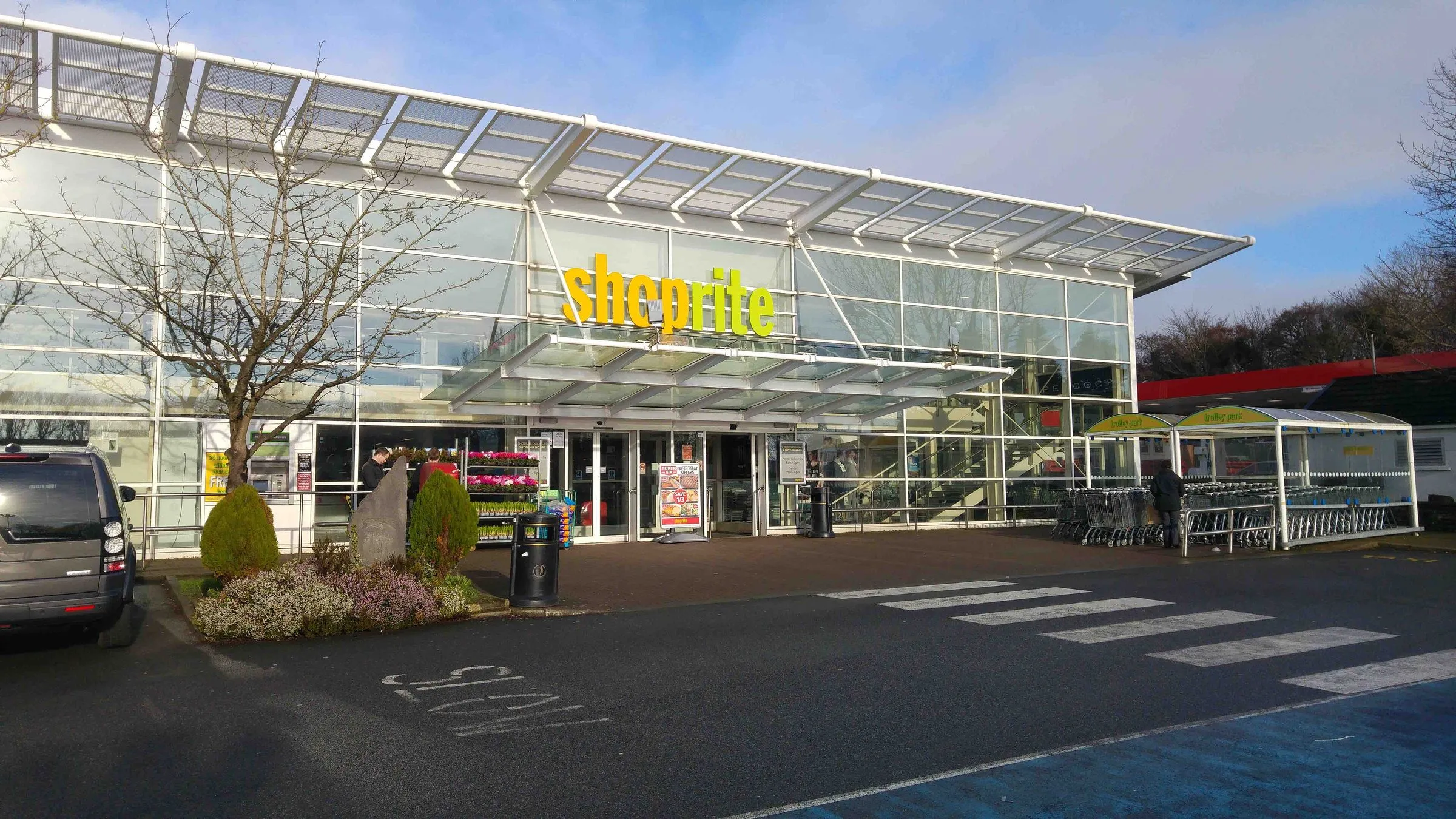 A large glass-fronted supermarket with a canopy over the entrance and a trolley shelter, at Little Switzerland in Douglas, photographed when it still carried Shoprite signs